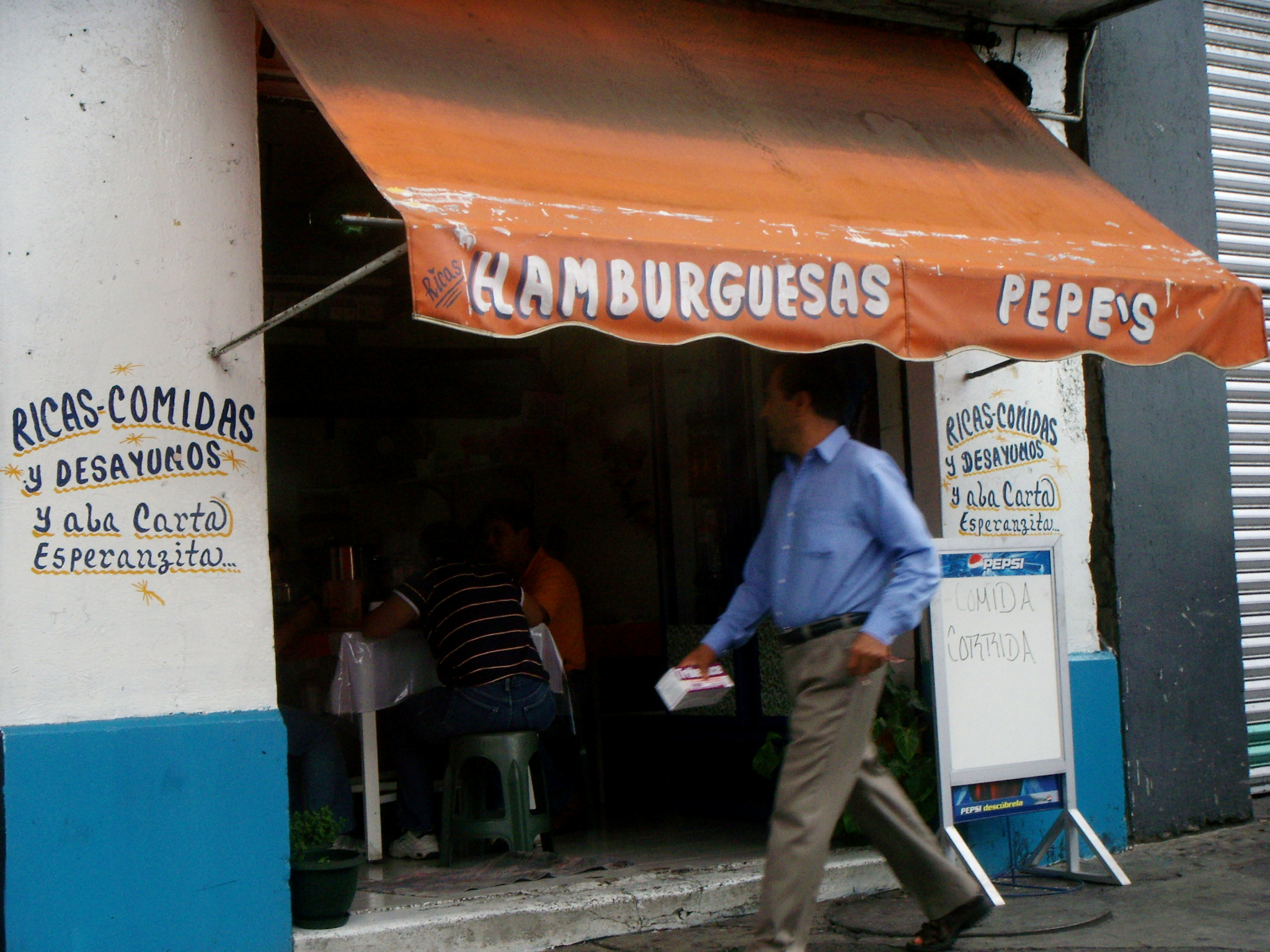 Blue hand-painted menu lettering on a white restaurant wall in Mexico City