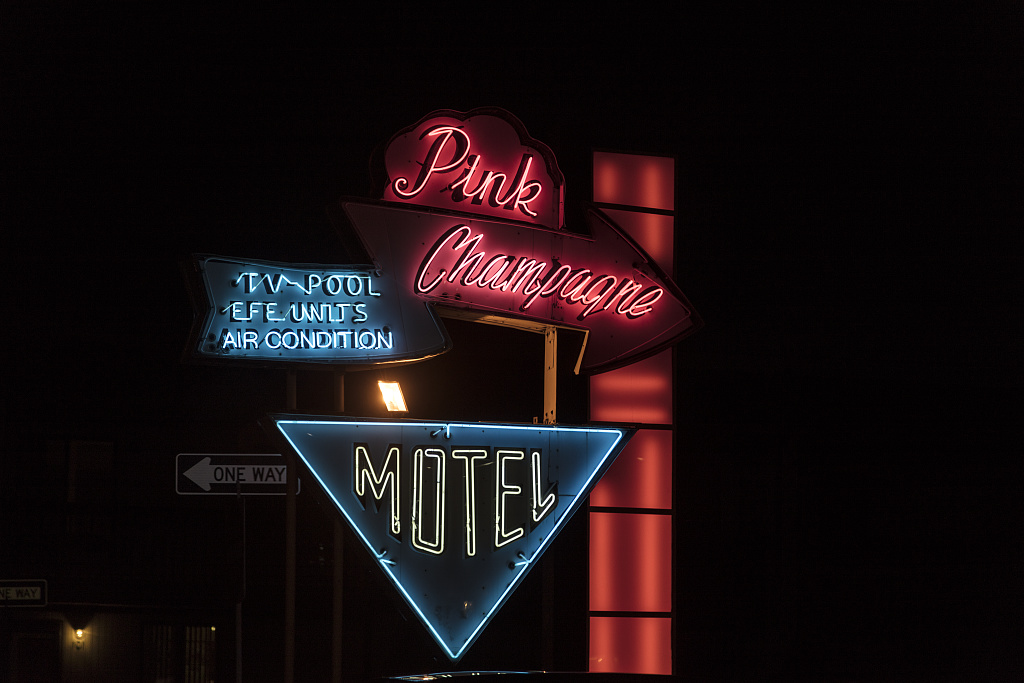 Pink Champagne Motel sign, with red script and blue neon lettering